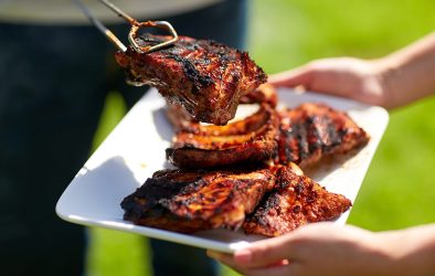 Gegrilltes Fleisch und Würstchen auf einem Teller beim Grillen im Freien.