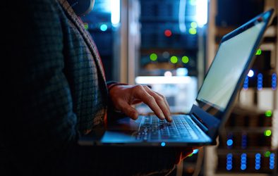 IT-Spezialist arbeitet mit Laptop im Serverraum – Symbolbild für Cybersicherheit und NIS-2 Richtlinie
