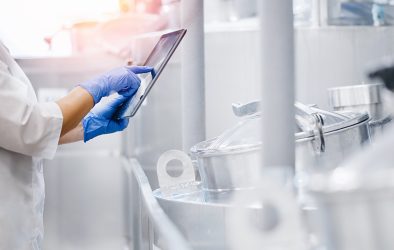 Mitarbeiterin in der Lebensmittelproduktion prüft Prozessdaten auf einem Tablet.