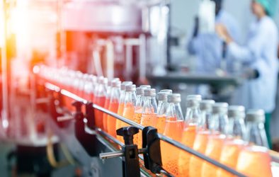 Abfüllanlage in der Lebensmittelindustrie mit Glasflaschen und Mitarbeitenden in Schutzkleidung