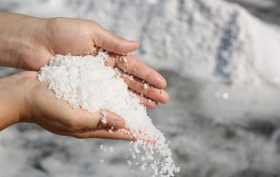 Person hält grobkörniges Salz in den Händen.